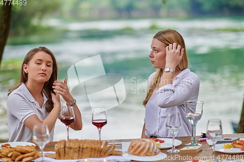 Image of girlfriends having picnic french dinner party outdoor