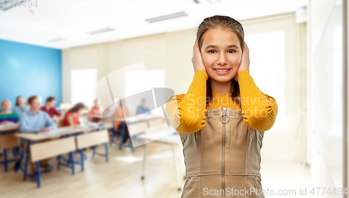 Image of student girl closing ears by hands at school