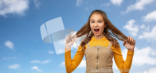 Image of scared young teenage girl holding her hair strands