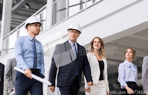 Image of business team in helmets walking along office