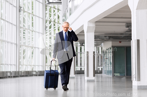 Image of worried senior businessman walking with travel bag