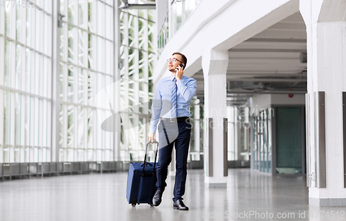 Image of businessman with travel bag calling on smartphone