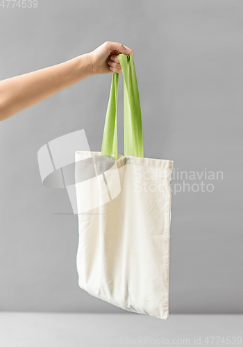 Image of hand holding reusable canvas bag for food shopping