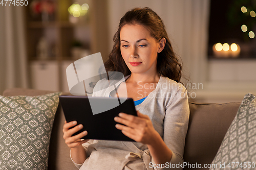 Image of happy woman with tablet pc at home in evening