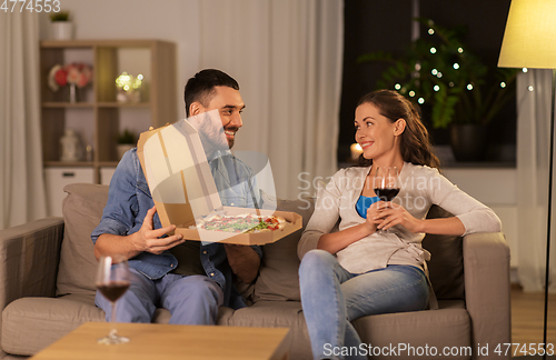 Image of happy couple eating takeaway pizza at home