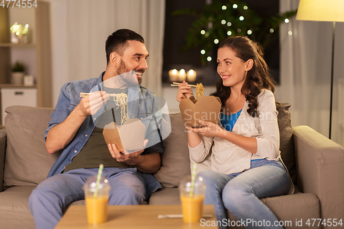 Image of happy couple eating takeaway noodles at home