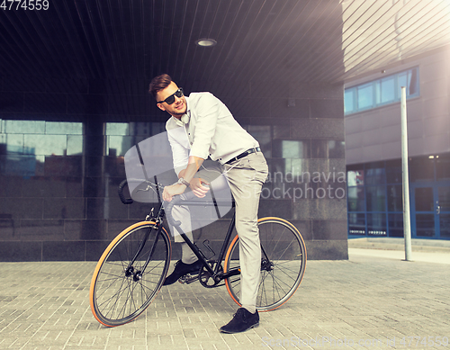 Image of man with bicycle and headphones on city street