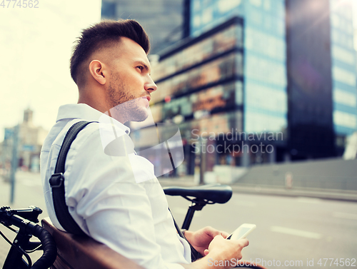 Image of man with smartphone and bicycle in city