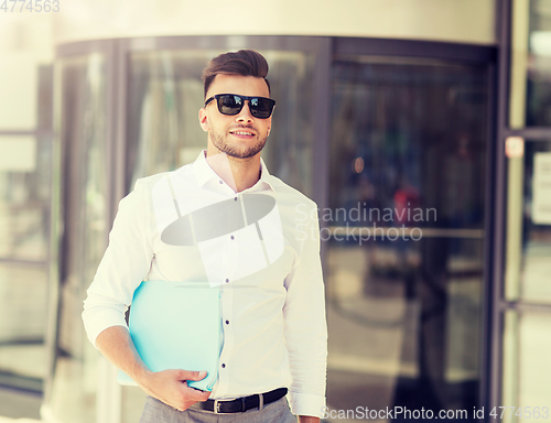 Image of young man with business file on city street
