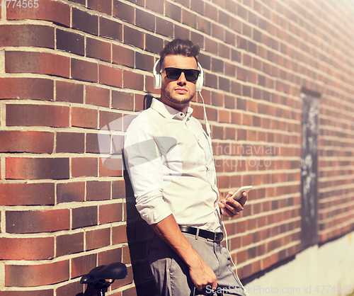 Image of man with headphones, smartphone and bicycle