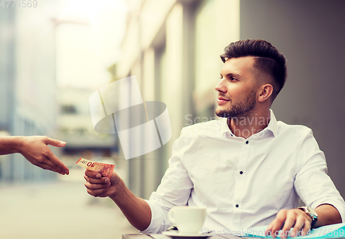 Image of man with euro money paying for coffee at cafe