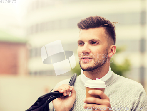 Image of young man with bag drinking coffee in city