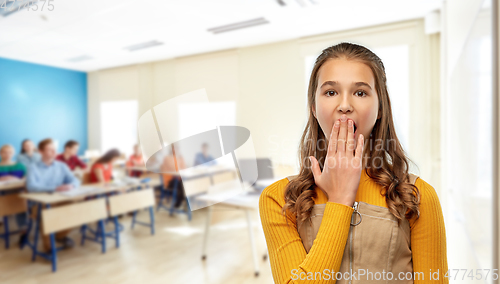 Image of student girl closing her mouth by hand at school