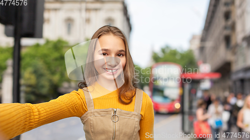 Image of happy teenage girl taking selfie over london city