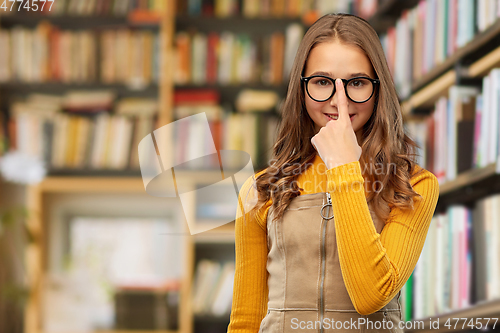 Image of smiling teenage student girl in glasses at library