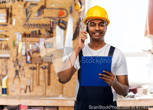 Image of indian builder with clipboard calling on cellphone