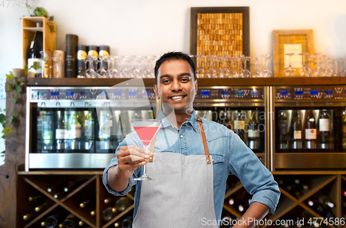 Image of indian barman with glass of cocktail at bar