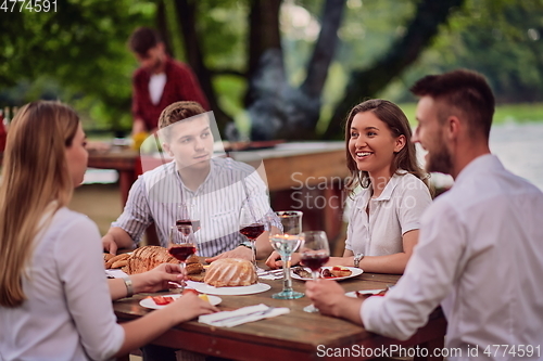 Image of friends having picnic french dinner party outdoor during summer holiday