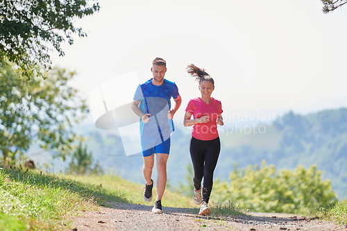 Image of couple enjoying in a healthy lifestyle while jogging on a country road