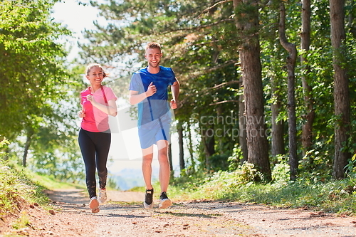 Image of couple enjoying in a healthy lifestyle while jogging on a country road