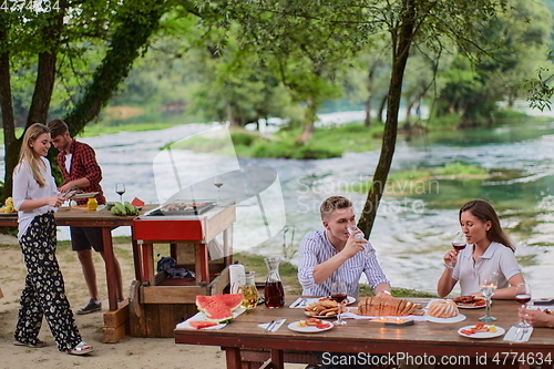 Image of friends having picnic french dinner party outdoor during summer holiday