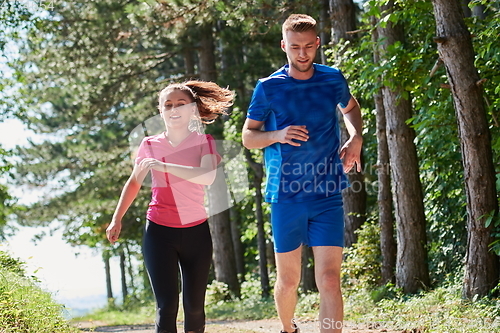 Image of couple enjoying in a healthy lifestyle while jogging on a country road