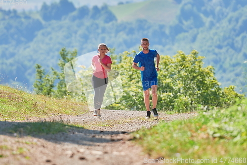 Image of couple enjoying in a healthy lifestyle while jogging on a country road