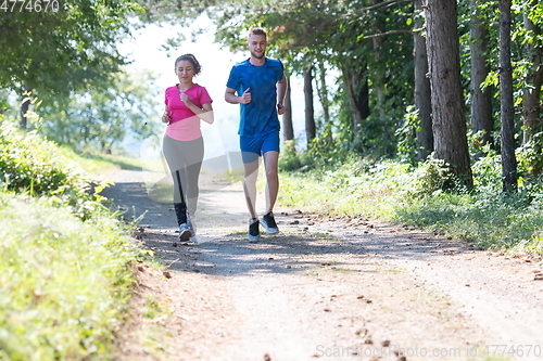 Image of couple enjoying in a healthy lifestyle while jogging on a country road