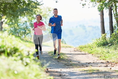 Image of couple enjoying in a healthy lifestyle while jogging on a country road