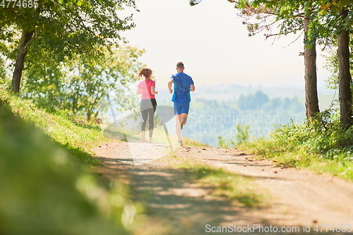 Image of couple enjoying in a healthy lifestyle while jogging on a country road