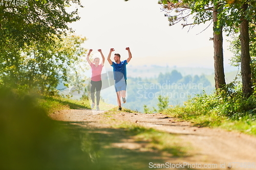 Image of couple enjoying in a healthy lifestyle while jogging on a country road