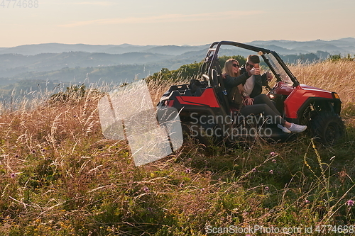 Image of couple enjoying beautiful sunny day taking selfie picture while driving a off road buggy