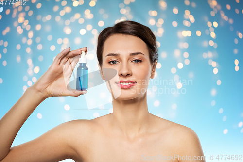 Image of beautiful young woman with bottle of serum