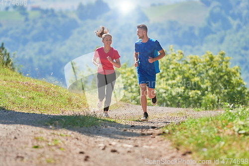 Image of couple enjoying in a healthy lifestyle while jogging on a country road