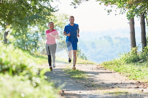 Image of couple enjoying in a healthy lifestyle while jogging on a country road