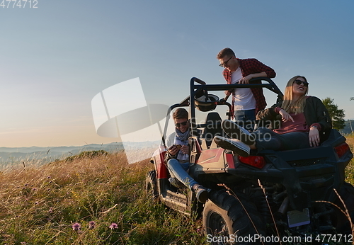 Image of group young happy people enjoying beautiful sunny day while driving a off road buggy car