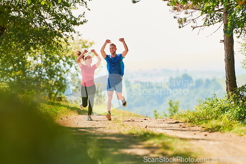 Image of couple enjoying in a healthy lifestyle while jogging on a country road