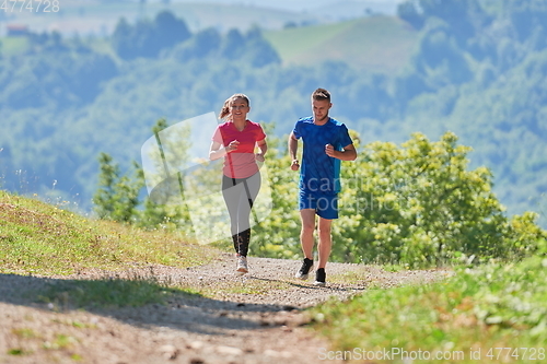 Image of couple enjoying in a healthy lifestyle while jogging on a country road