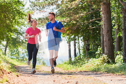 Image of couple enjoying in a healthy lifestyle while jogging on a country road