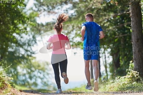 Image of couple enjoying in a healthy lifestyle while jogging on a country road