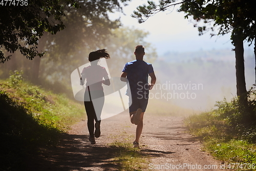 Image of couple enjoying in a healthy lifestyle while jogging on a country road