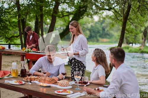 Image of friends having picnic french dinner party outdoor during summer holiday