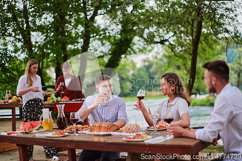 Image of friends having picnic french dinner party outdoor during summer holiday