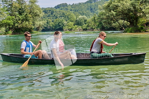 Image of Group adventurous explorer friends are canoeing in a wild river