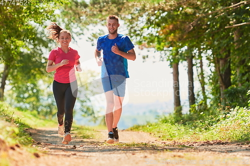 Image of couple enjoying in a healthy lifestyle while jogging on a country road