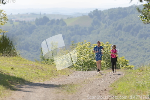 Image of couple enjoying in a healthy lifestyle while jogging on a country road