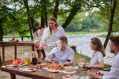 Image of friends having picnic french dinner party outdoor during summer holiday