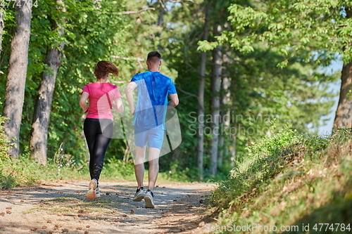 Image of couple enjoying in a healthy lifestyle while jogging on a country road