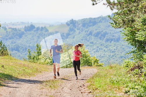 Image of couple enjoying in a healthy lifestyle while jogging on a country road