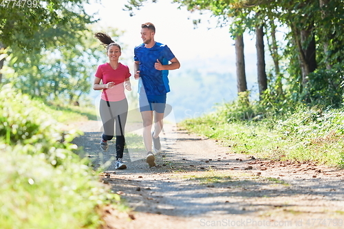 Image of couple enjoying in a healthy lifestyle while jogging on a country road